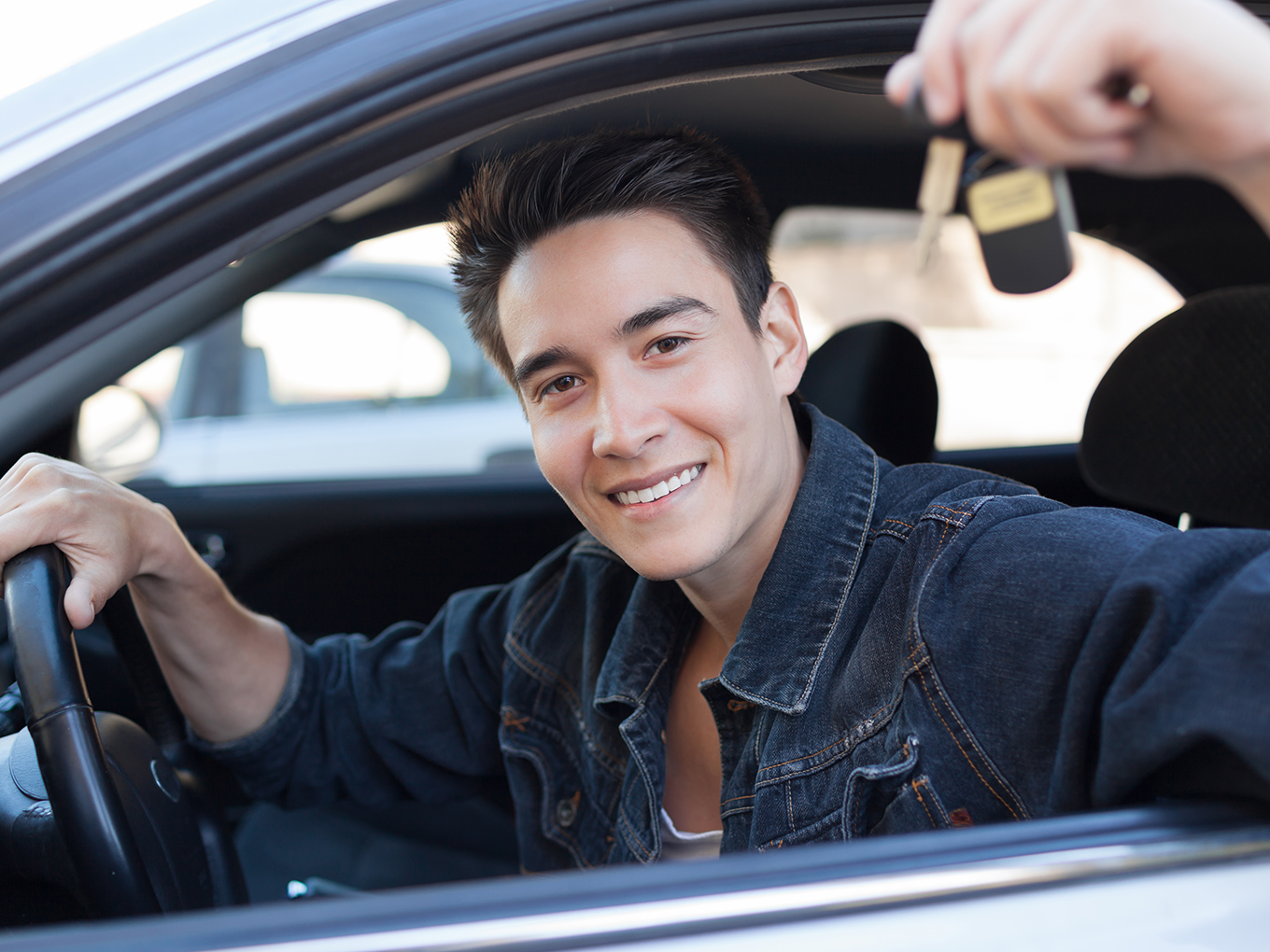 Approval Heroes - A Commitment to Excellence Young male sitting in car celebrating getting the keys to his new vehicle with car key in hand and other hand on steering wheel
