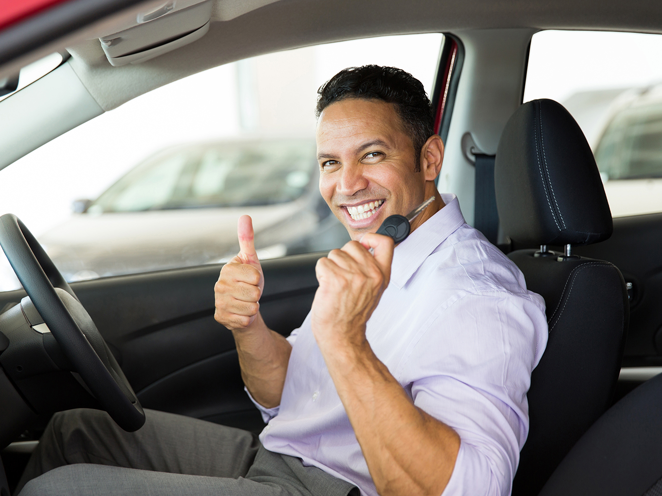 Experience stress-free car shopping with Approval Heroes Happy man sitting inside his new car holding car key