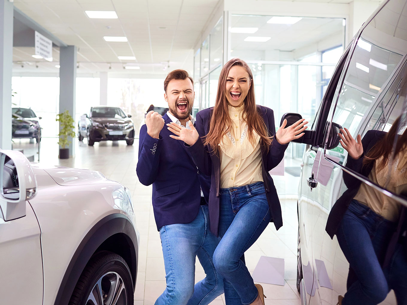 A joyful couple celebrating after securing an auto loan and purchasing a new car at a dealership