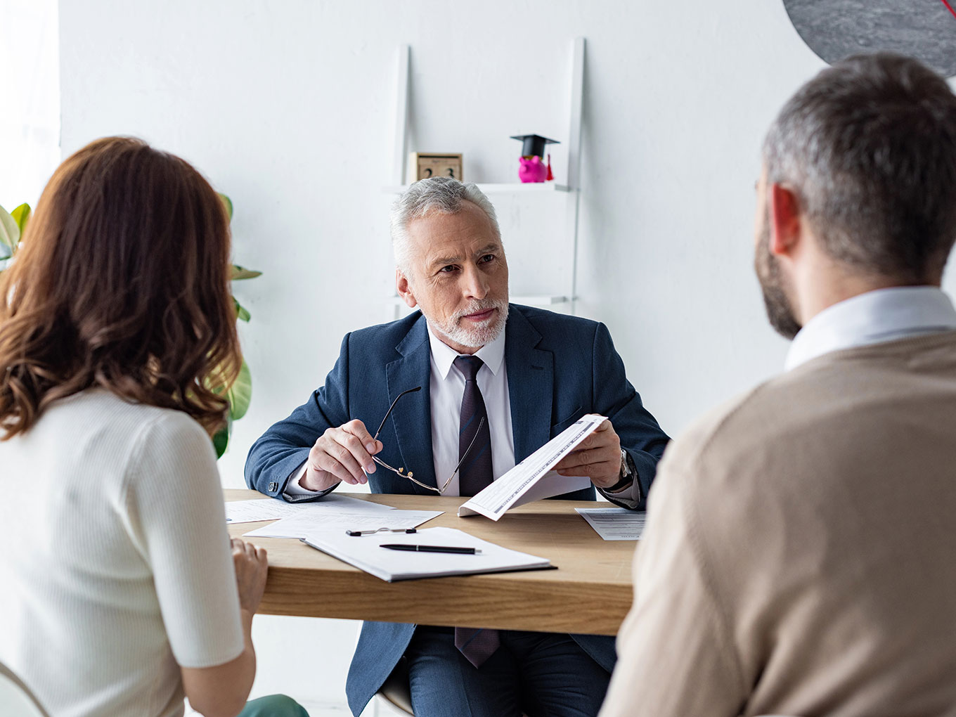 A financial advisor consulting with a couple about their auto loan options, discussing documents in a professional setting