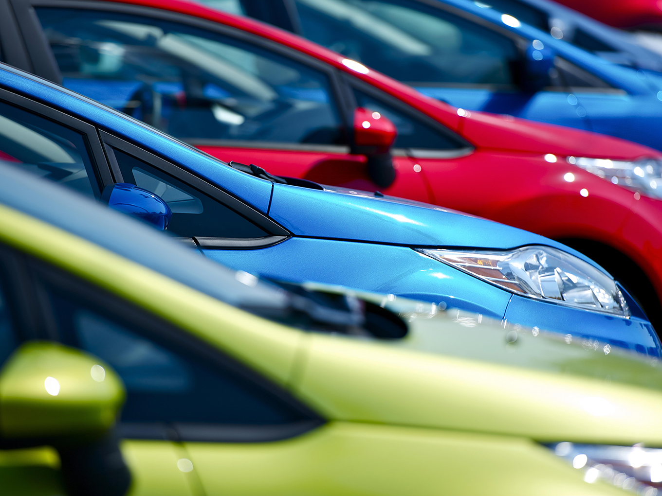 Wide selection of vehicles at our diverse network of dealerships A row of cars in different colors parked on a dealership lot