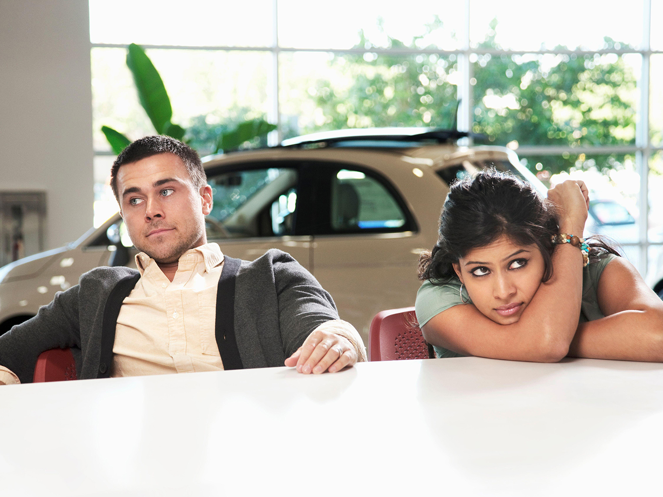 Feeling overwhelmed? Let Approval Heroes simplify your car loan process and ease the stress of car shopping. Stressed couple in a car dealership, showcasing the often overwhelming car buying experience.