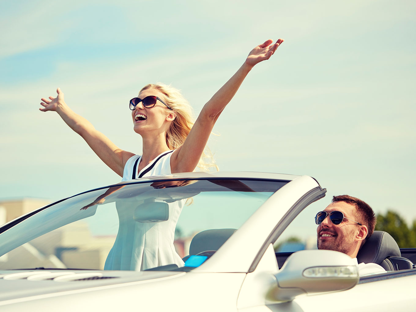 Drive with Confidence - Happy Couple in Convertible A joyful man and woman driving in an open top convertible on a sunny day, expressing celebration and confidence in achieving car financing goals.