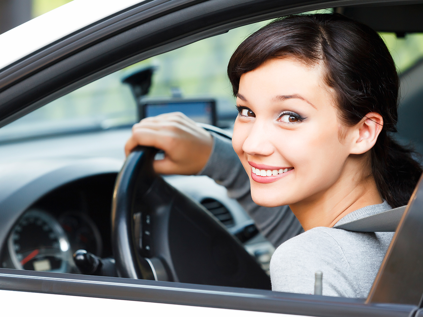 Happy Customer Dirving Car Away Pretty woman smiling in the drivers seat of a new car holding the steering wheel