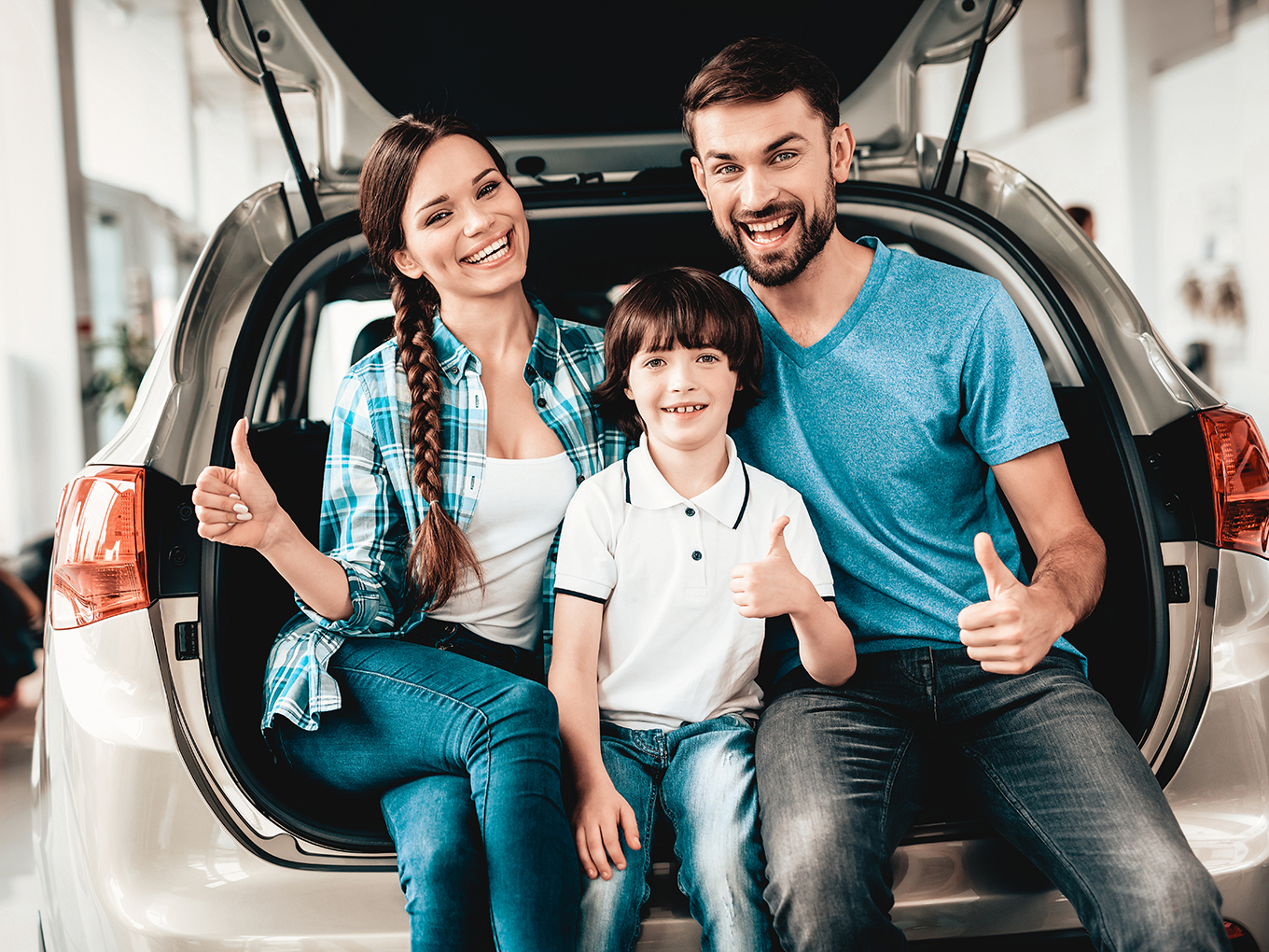 Happy Family New Car Purchase Family are stitting in the trunk of a new car with thumbs up.
