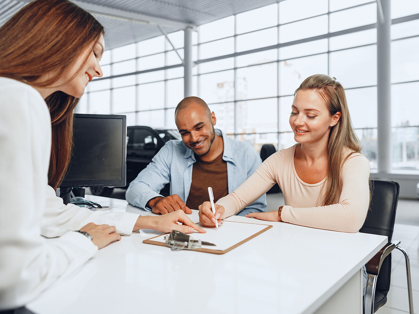 Car Buyer Signing Paperwork with Dealer Representative Car buyer signing paperwork with dealer representative