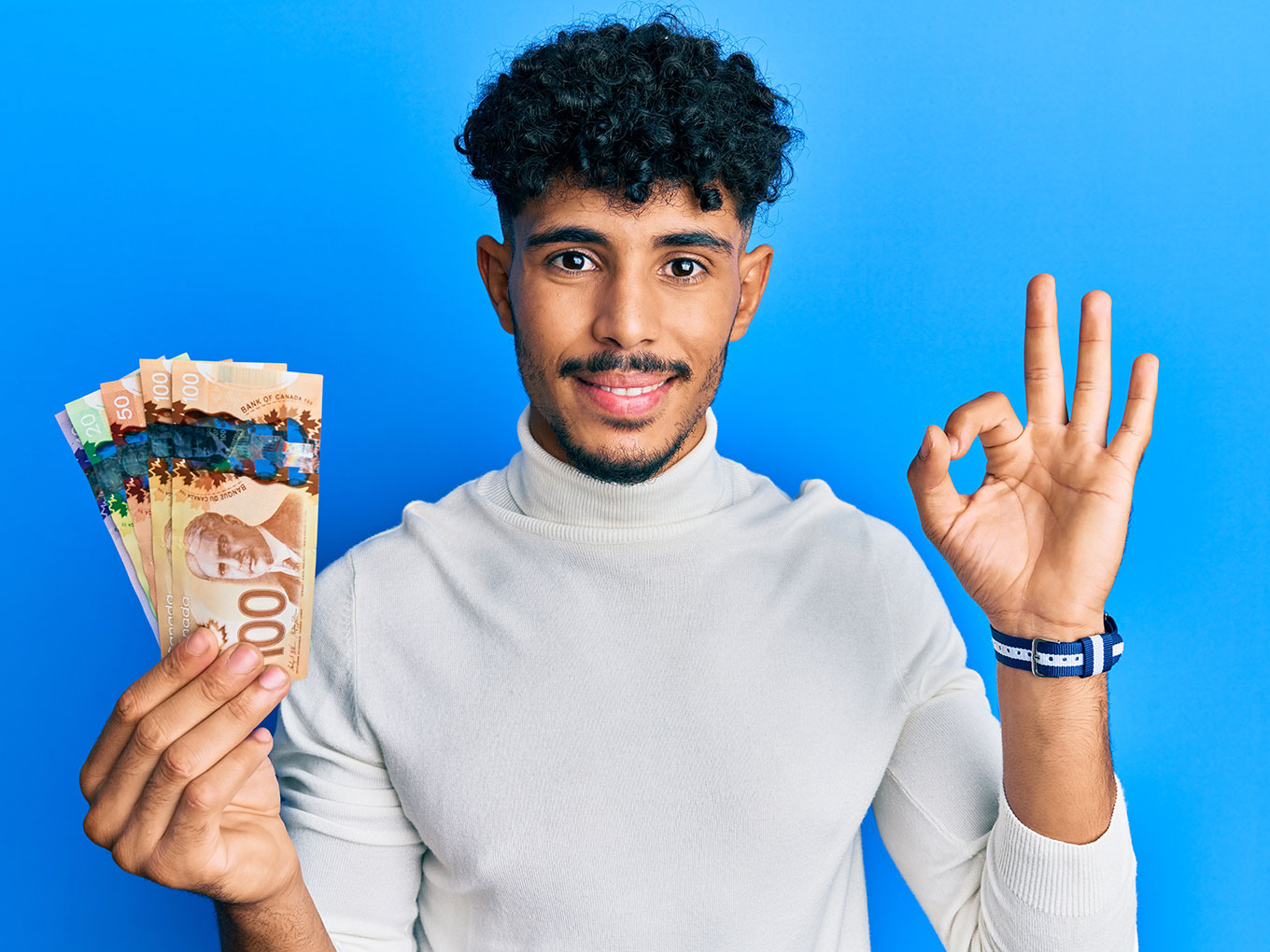 Image of a confident young man holding Canadian dollar bills, symbolizing the financial freedom and empowerment gained through Approval Heroes' car title loan services.